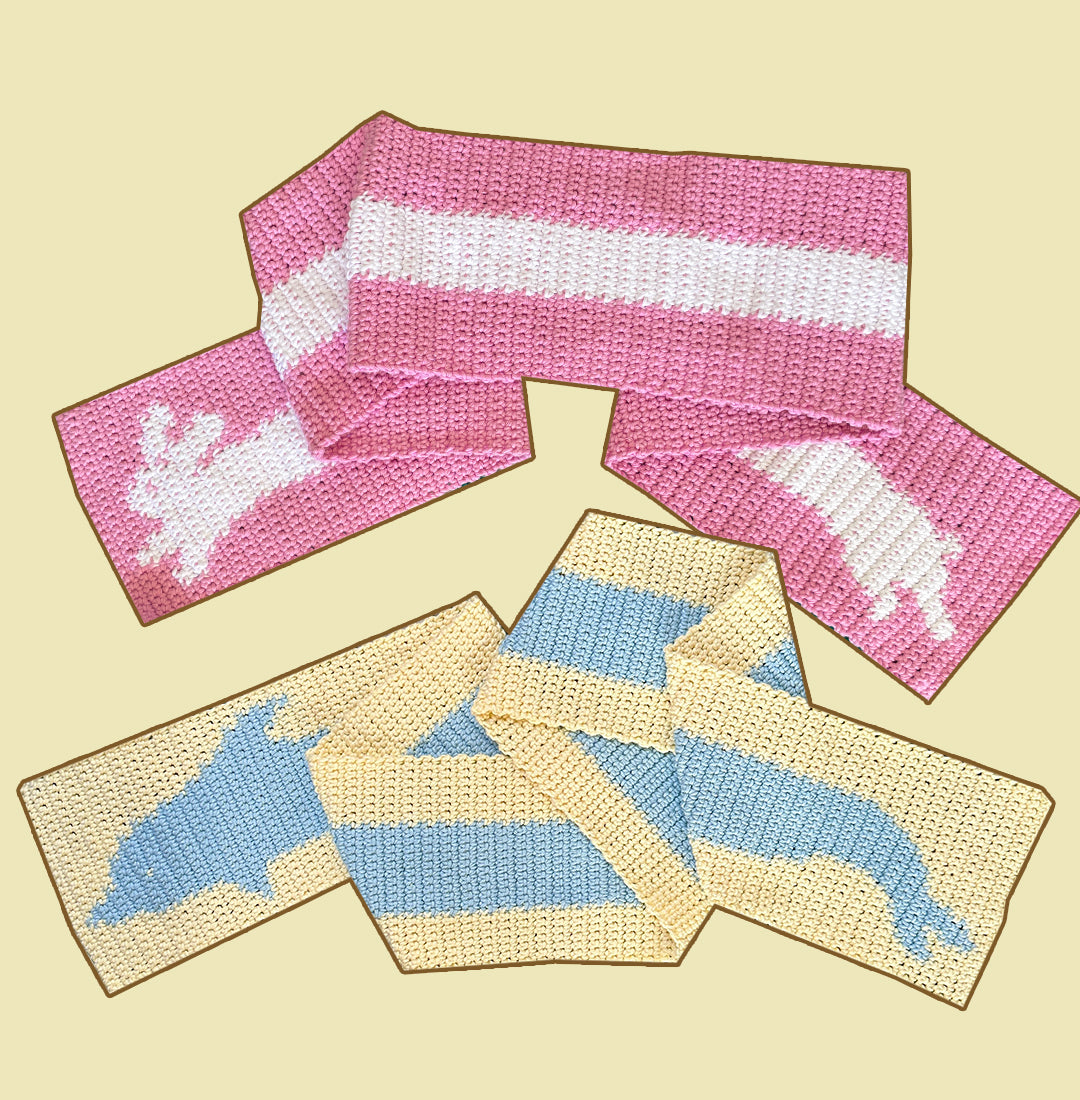 A stylish pink and white scarf from the "Crochet pattern combo pack ✧ Pet scarves" by devout hand, featuring a charming reindeer pattern on both ends, is displayed on a checkered green and white rug.